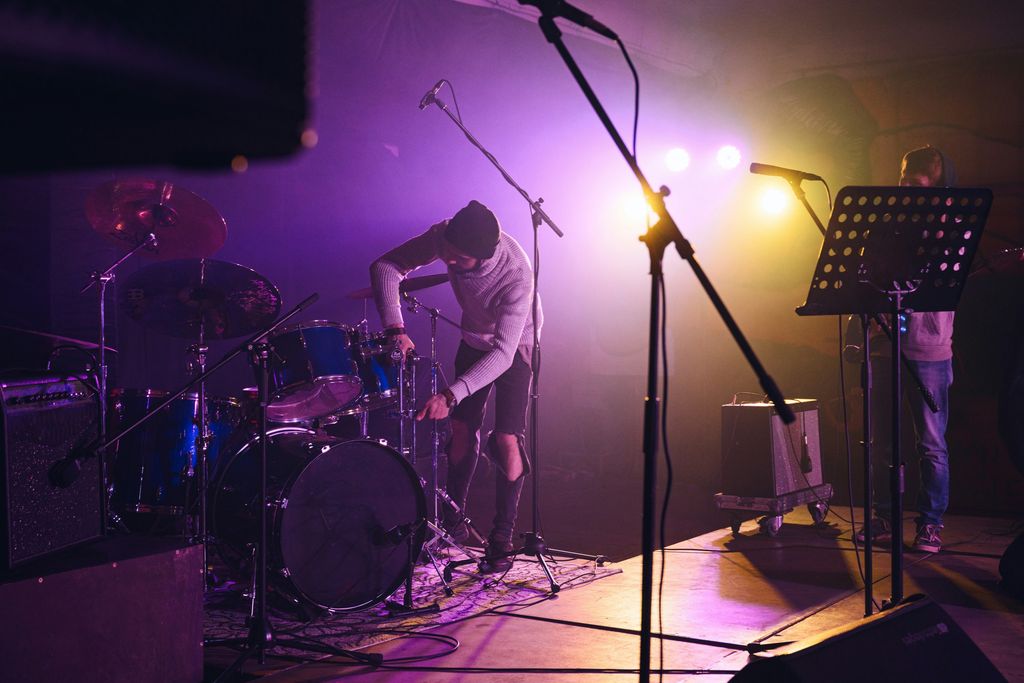 Someone is setting up a drum kit on a stage
