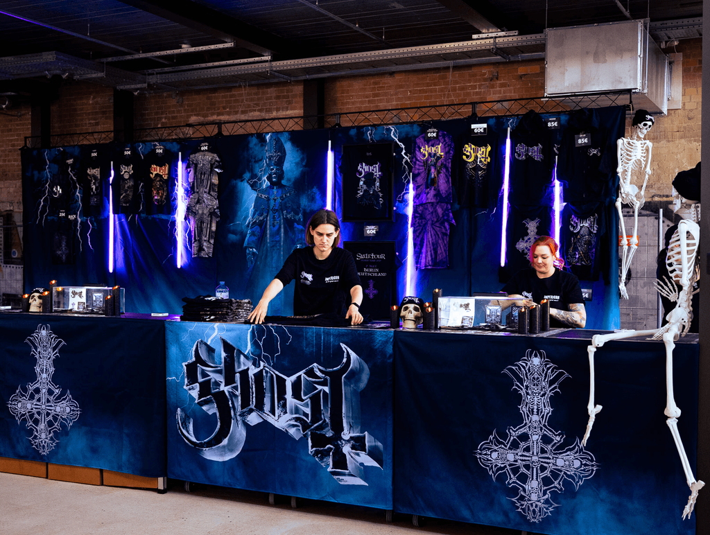 A sales booth in a warehouse for the band Ghost
