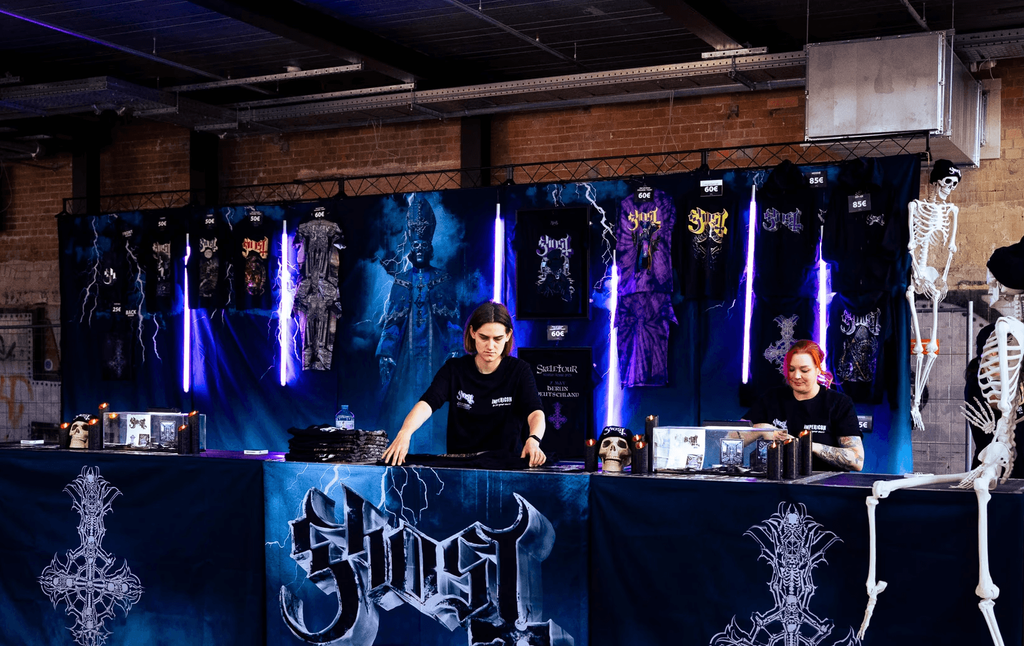 A sales booth in a warehouse for the band Ghost