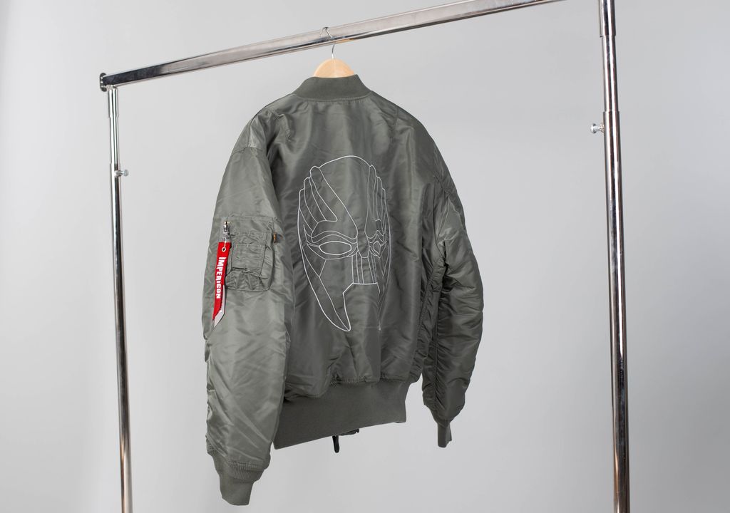 A jacket with the Marsimoto mask embroidered on the back, hung on a clothing rack