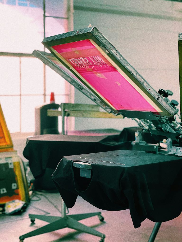 A screen printing machine is printing a T-shirt.